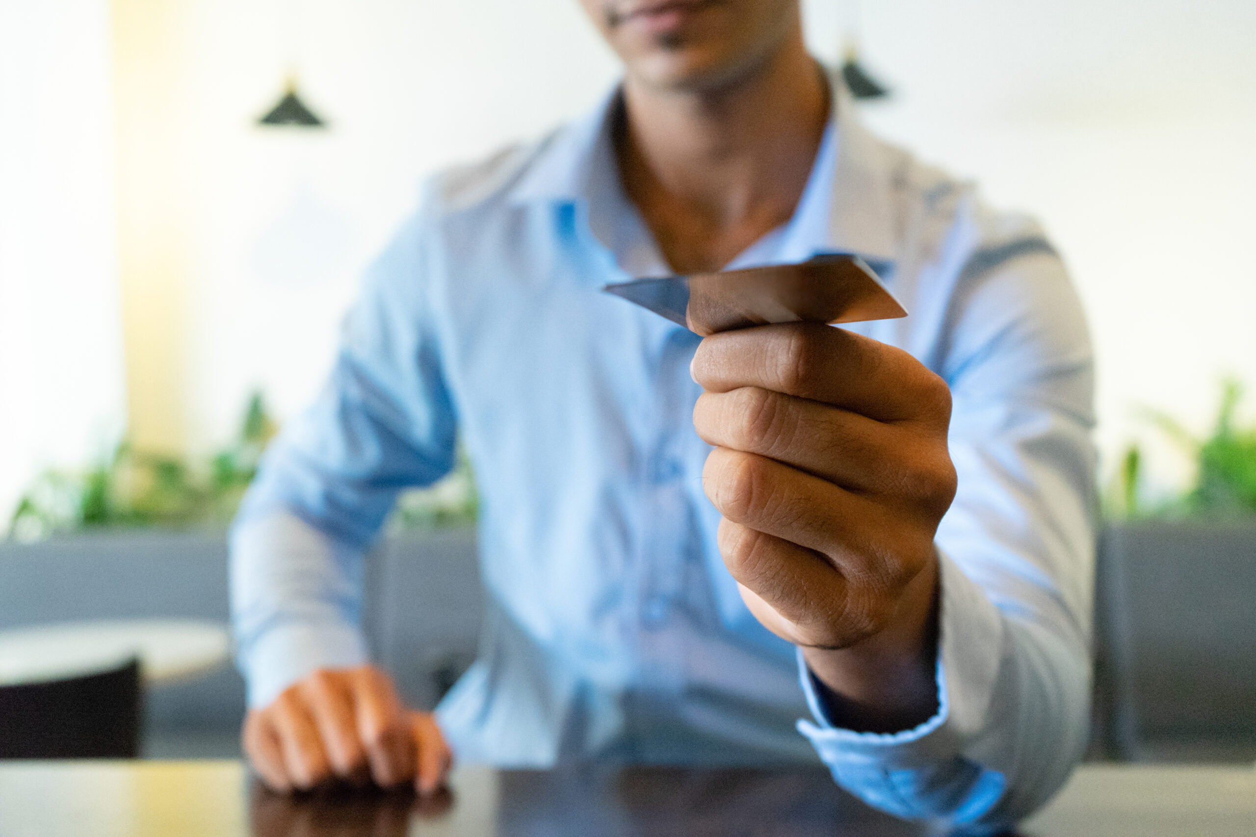 Close-up of Indian businessman hand giving business card. Young man sitting paying with credit card at cafe. Business identity concept